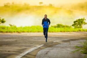 man in track suit jogging on concrete road, road running