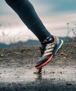 a person walking in a puddle of water, trail running shoes