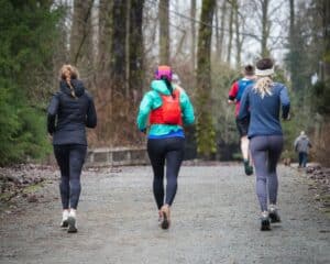 a group of people running down a dirt road, trail running shoes