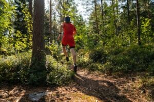 a man in red running through a forest, trail running