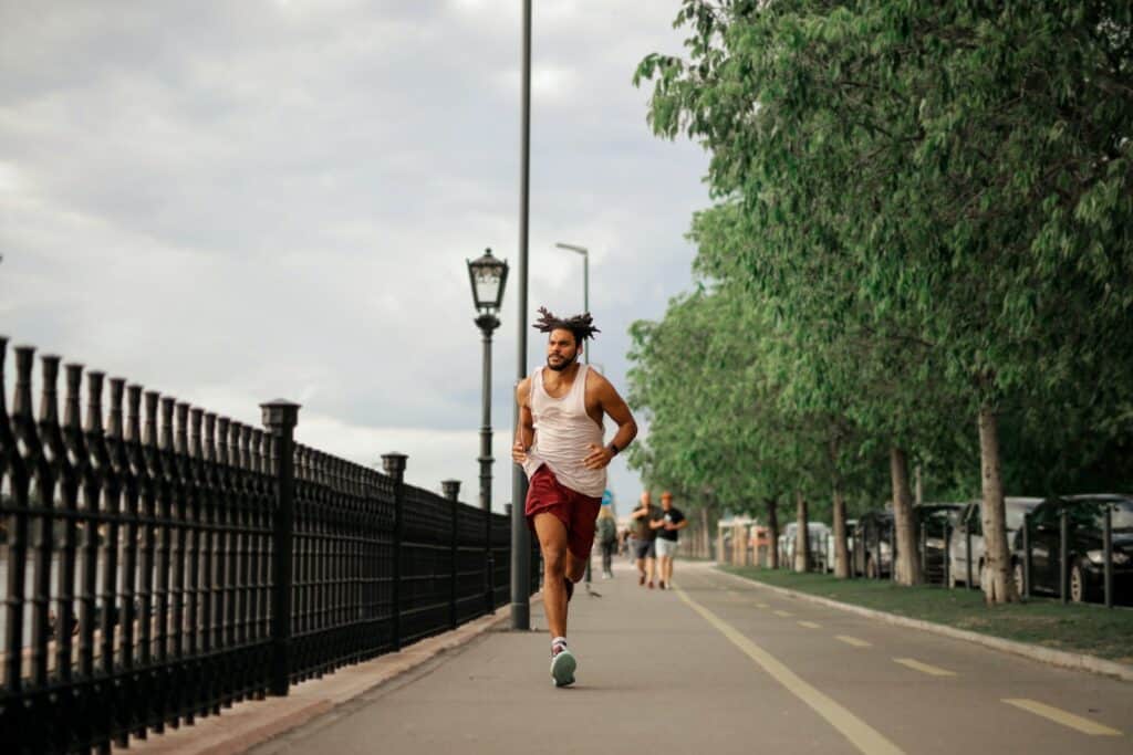 running, Man in White Tank Top and Red Shorts Running on Road