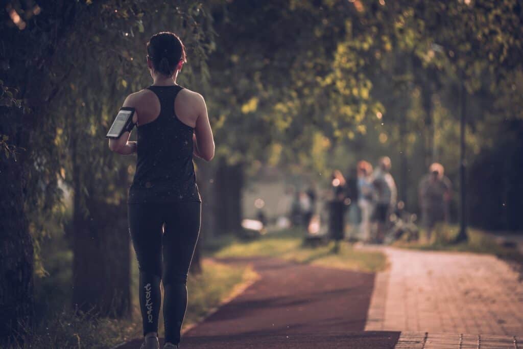 running, woman in black tank top and black pants walking on sidewalk during daytime