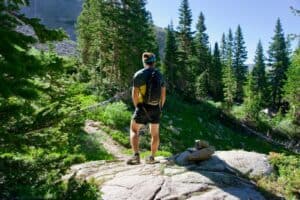 man standing in front of pine trees