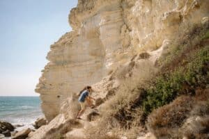 A Man Walking Uphill on a Rocky Landscape