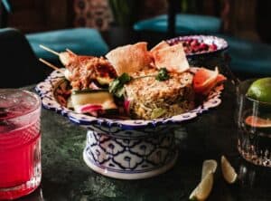 a bowl of food on a table next to a drink