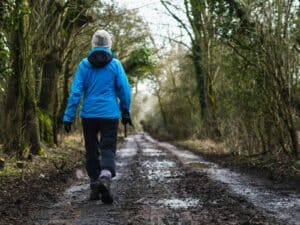 person in blue hoodie walking on dirt road during daytime